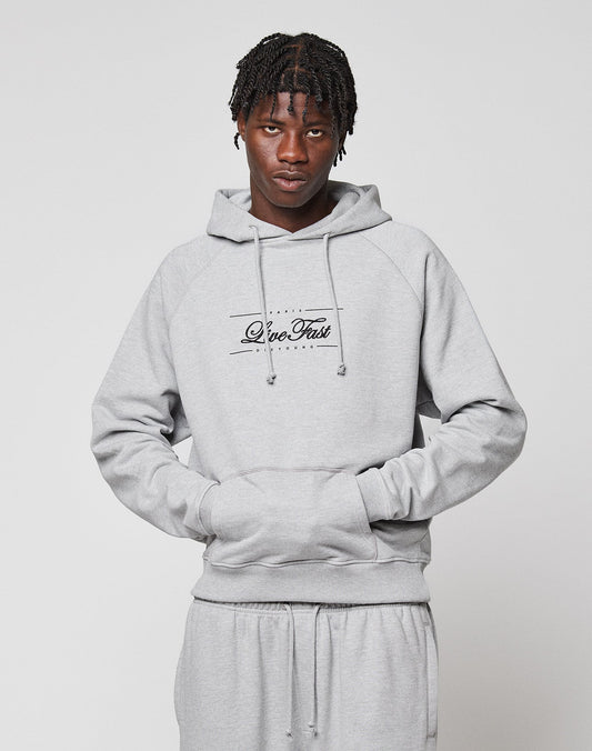 A person with short braided hair and a neutral expression models the light gray LFDY Embroidery Hooded by LIVE FAST DIE YOUNG, featuring “Live Fast” script on the front and matching sweatpants, against a plain white background.