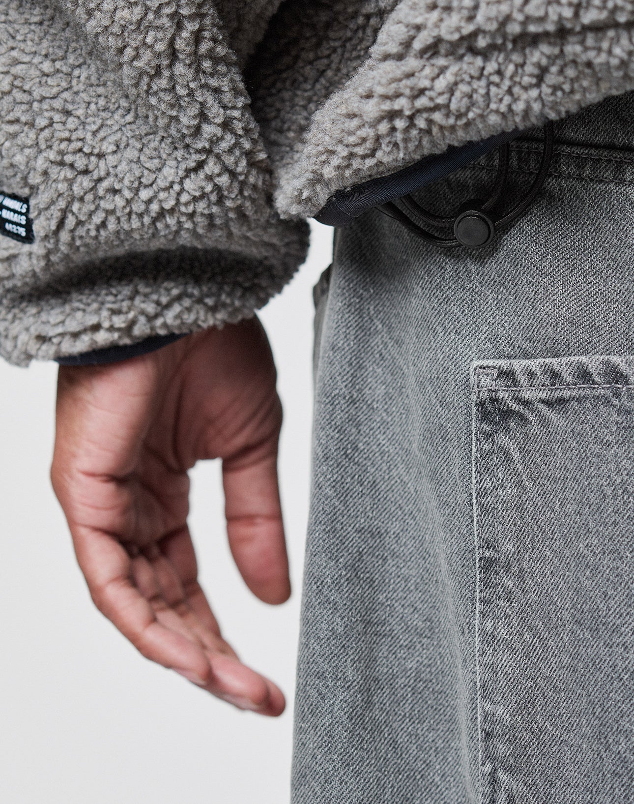 A close-up of a hand slipping into the Eingrifftaschen, highlighting the comfort and style of the LFDY Teddy Hooded by LIVE FAST DIE YOUNG.