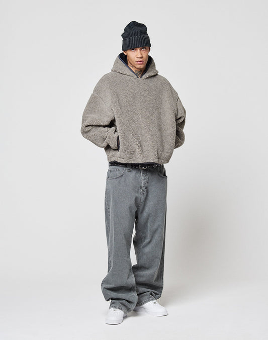 A person wearing the gray LFDY Teddy Hooded by LIVE FAST DIE YOUNG, baggy gray oversize jeans, a black beanie, and white sneakers stands against a plain white background with hands in pockets.