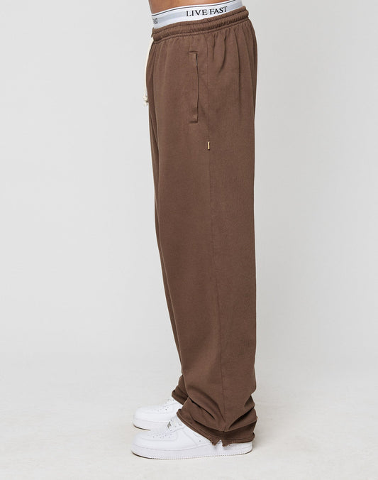 A person wearing loose-fitting LFDY Lightweight Jogger sweatpants by LIVE FAST DIE YOUNG, white sneakers, and a visible white waistband with LIVE FAST text, standing sideways against a plain white background.