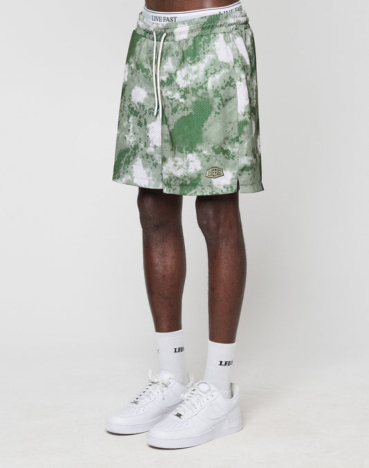 A person wears green and white LFDY Mesh Shorts by LIVE FAST DIE YOUNG (Regular Fit, elastic waistband), white LIVE FAST socks, and white Nike sneakers. Only their legs and lower torso are shown against a plain white background.