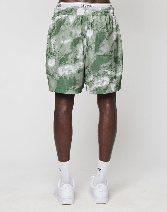 Someone stands with their back to the camera, wearing green and white LFDY Mesh Shorts by LIVE FAST DIE YOUNG, white socks, white sneakers, and a white waistband underwear, all set against a plain white background.