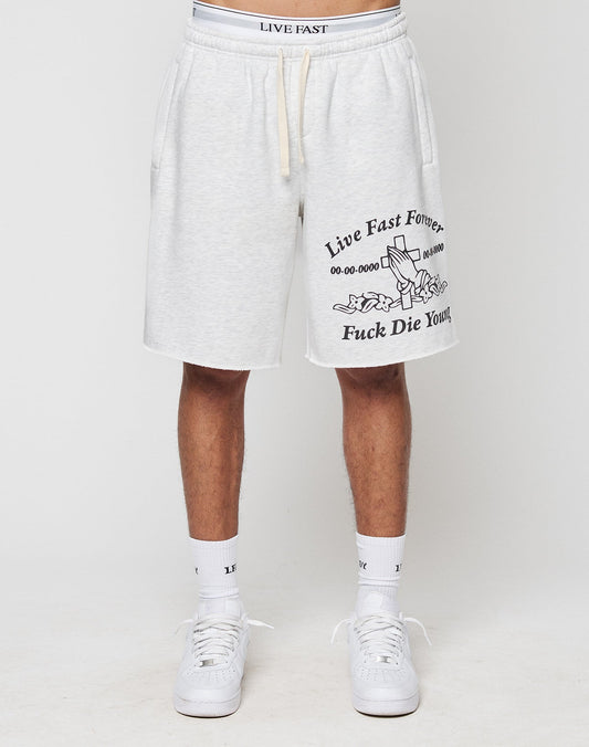A person wears light gray LFDY Praying Shorts by LIVE FAST DIE YOUNG, featuring black “Live Fast Forever” and “Fuck Die Young” prints, a tombstone graphic, Elastikbund, seitliche Eingrifftaschen, white socks, and sneakers.