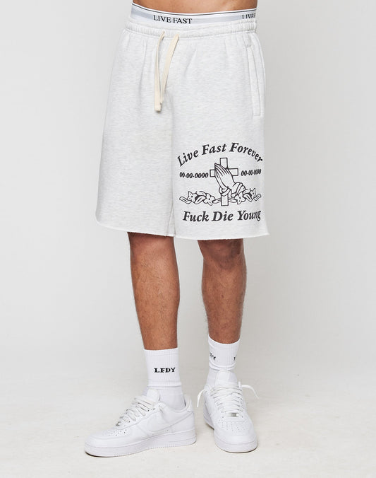 Someone wears light gray LFDY Praying Shorts by LIVE FAST DIE YOUNG with elastic waistband, side pockets, urn and flower graphic, Live Fast Forever Fuck Die Young text, white LFDY socks, white sneakers, and a matching LIVE FAST waistband.