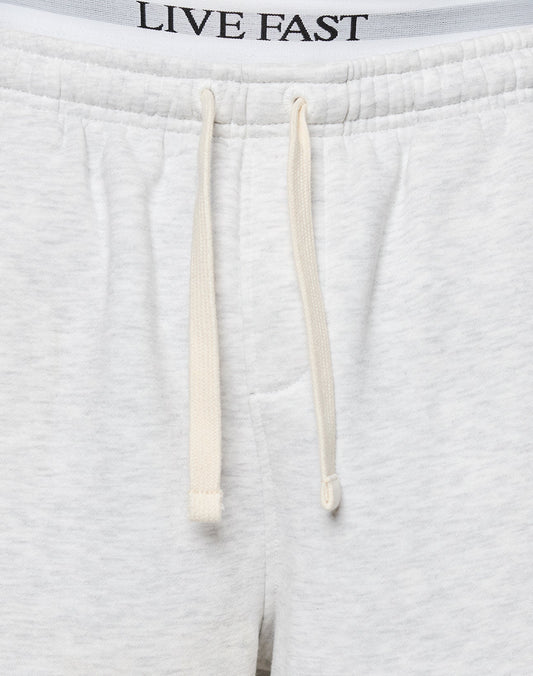 Close-up of LFDY Praying Shorts by LIVE FAST DIE YOUNG, featuring a white design with an elastic waistband, cream drawstrings, side pockets, and LIVE FAST printed on the inner waistband.