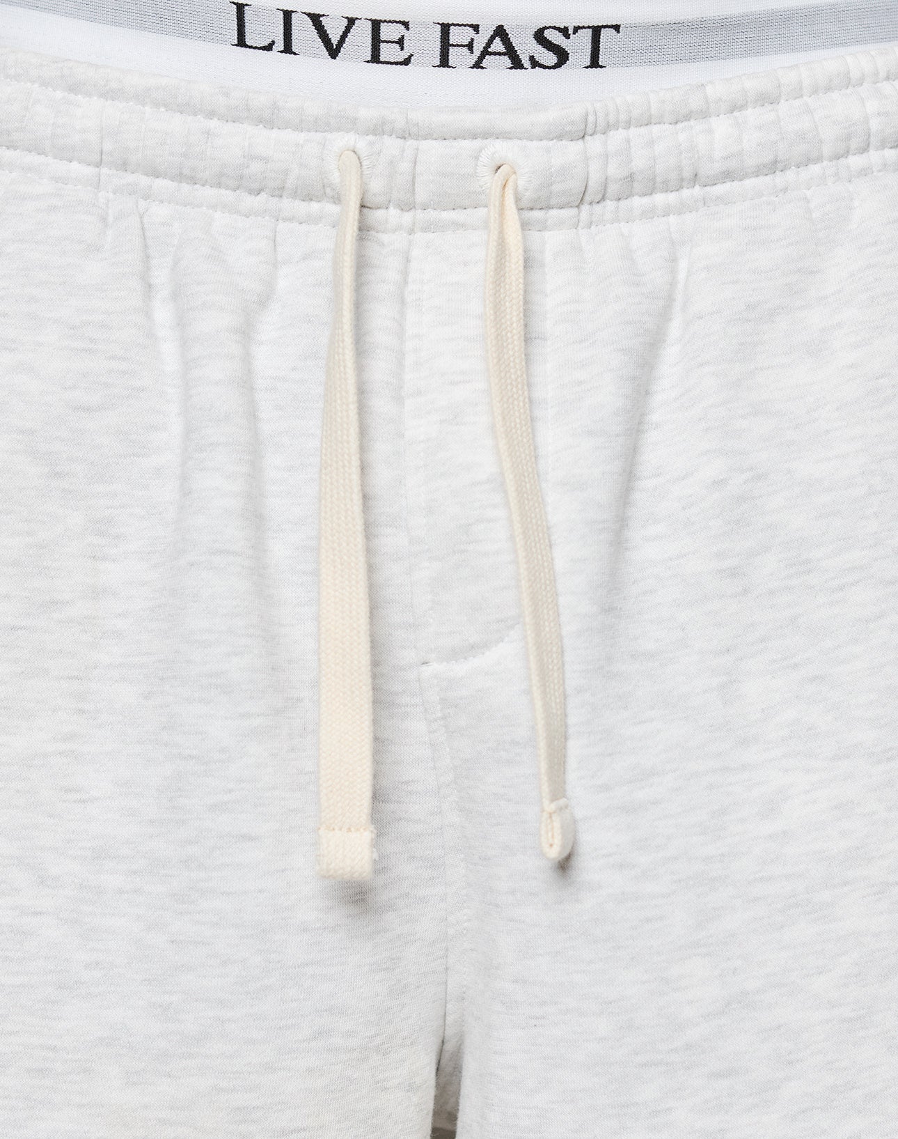 Close-up of LFDY Praying Shorts by LIVE FAST DIE YOUNG, featuring a white design with an elastic waistband, cream drawstrings, side pockets, and LIVE FAST printed on the inner waistband.
