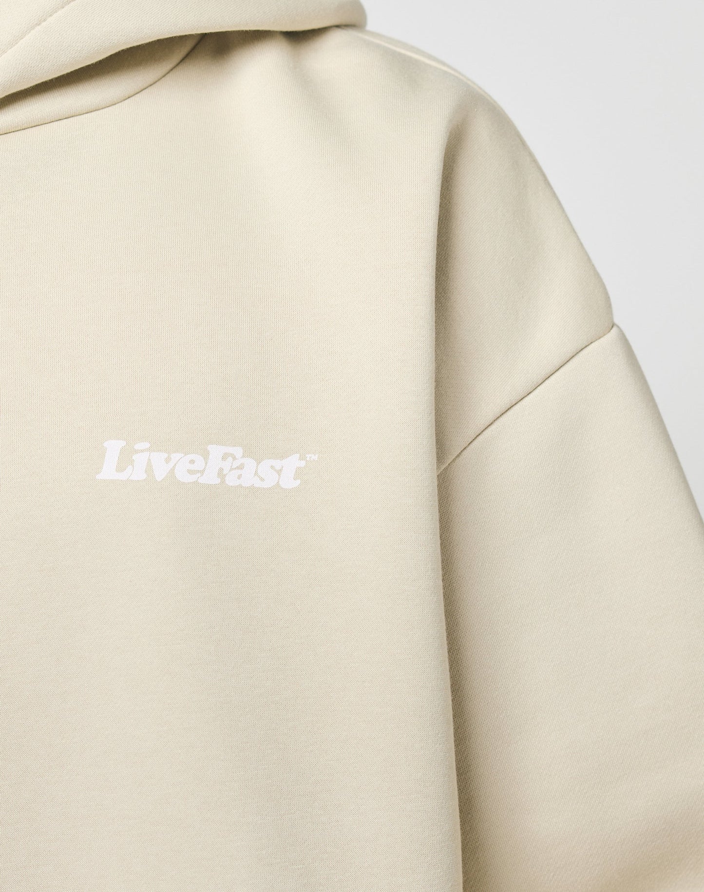 A close-up of the Basic 360 Hooded by LIVE FAST DIE YOUNG, an oversize beige hoodie made from soft Baumwolle and Polyester, with LiveFast printed in white on the chest.