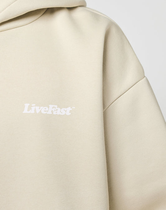 A close-up of the Basic 360 Hooded by LIVE FAST DIE YOUNG, an oversize beige hoodie made from soft Baumwolle and Polyester, with LiveFast printed in white on the chest.