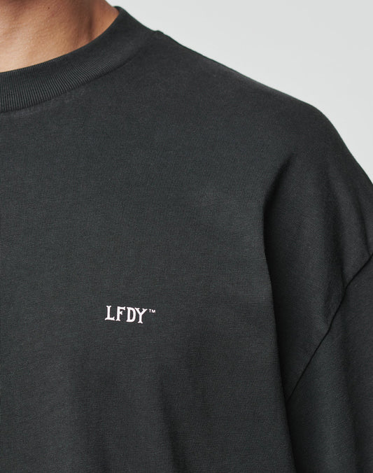 A person wears a black LFDY Flip Phone Tee by LIVE FAST DIE YOUNG, showing the upper torso and part of the neck against a plain background. Ideal for cotton lovers.