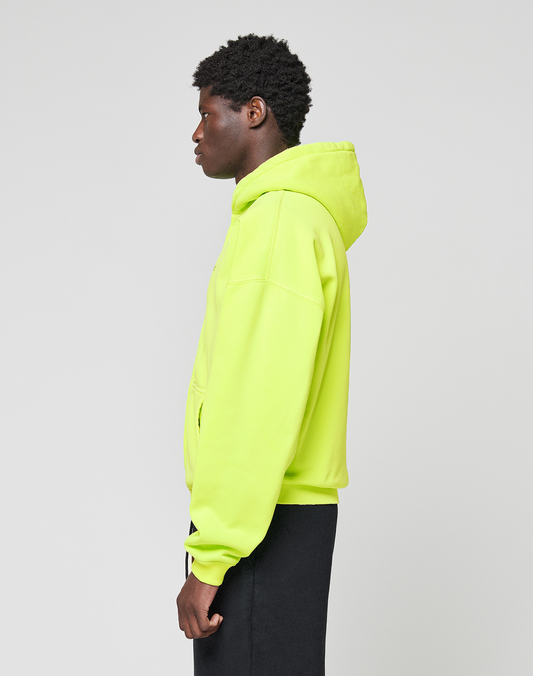 A person in a neon yellow LIVE FAST DIE YOUNG Basic Hooded Zip and black pants stands in profile against a plain light gray background.