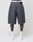 A person, back to the camera against a plain white background, wears baggy fit LIVE FAST DIE YOUNG LFDY Jorts with a leather patch, white LIVFAST socks, and white sneakers.
