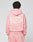 A person with short, twisted hair wears a pink LIVE FAST DIE YOUNG Basic 360 Hooded and matching pants. The hoodie has bold front and back print, sturdy topstitching, and white text. The background is plain.