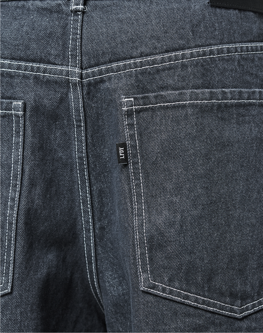 Close-up of the back of LFDY Jorts by LIVE FAST DIE YOUNG—dark blue baggy denim with two back pockets, white stitching, and a small black JAPY label near the right pocket.
