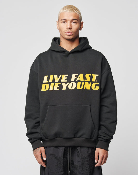 A man with short blond hair wears a black LFDY Drift Hooded sweatshirt by LIVE FAST DIE YOUNG, featuring bold yellow and white LIVE FAST. DIE YOUNG text. He faces the camera against a plain white background.