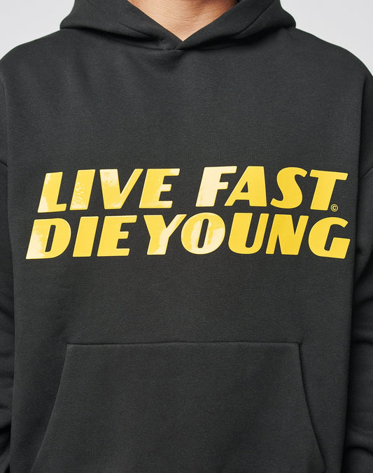 A person wears the LFDY Drift Hooded by LIVE FAST DIE YOUNG, an oversized black Baumwolle hoodie featuring bold yellow LIVE FAST, DIE YOUNG text on the front.