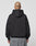 A person with a shaved head and a head tattoo is seen from behind, wearing the black LIVE FAST DIE YOUNG LFDY Gambling Hooded (360 GSM, oversize fit) and gray jeans against a plain light background.