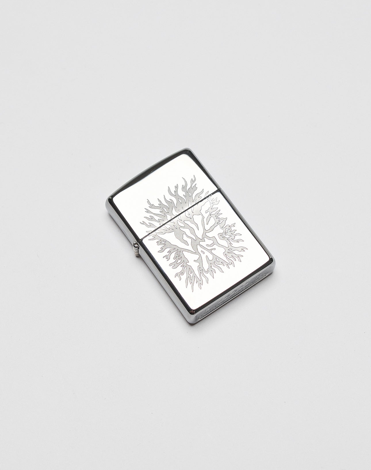 A silver rectangular LFDY x Zippo lighter by LIVE FAST DIE YOUNG features an engraved flame design on its aluminium case, displayed on a plain white background.| plain 