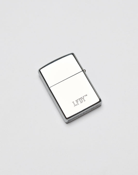 The LFDY x Zippo lighter by LIVE FAST DIE YOUNG features a silver rectangular Aluminium-Gehäuse with LFDY engraved on the front, shown on a plain white background.