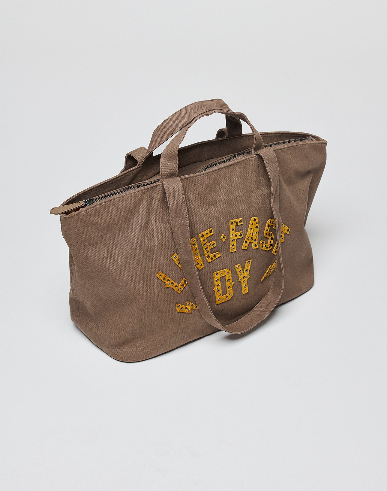 The LFDY Tote Bag by LIVE FAST DIE YOUNG is a brown canvas bag with two short handles, a zipper, a secure laptop compartment, and “THE FAST BOY” in yellow cheetah-print letters on the side, shown on a plain white background.