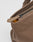 Close-up of the LFDY Tote Bag by LIVE FAST DIE YOUNG: a brown canvas tote with a black zipper partially open, revealing yellow fabric inside. The matching brown pull and dedicated laptop compartment offer secure, stylish storage.
