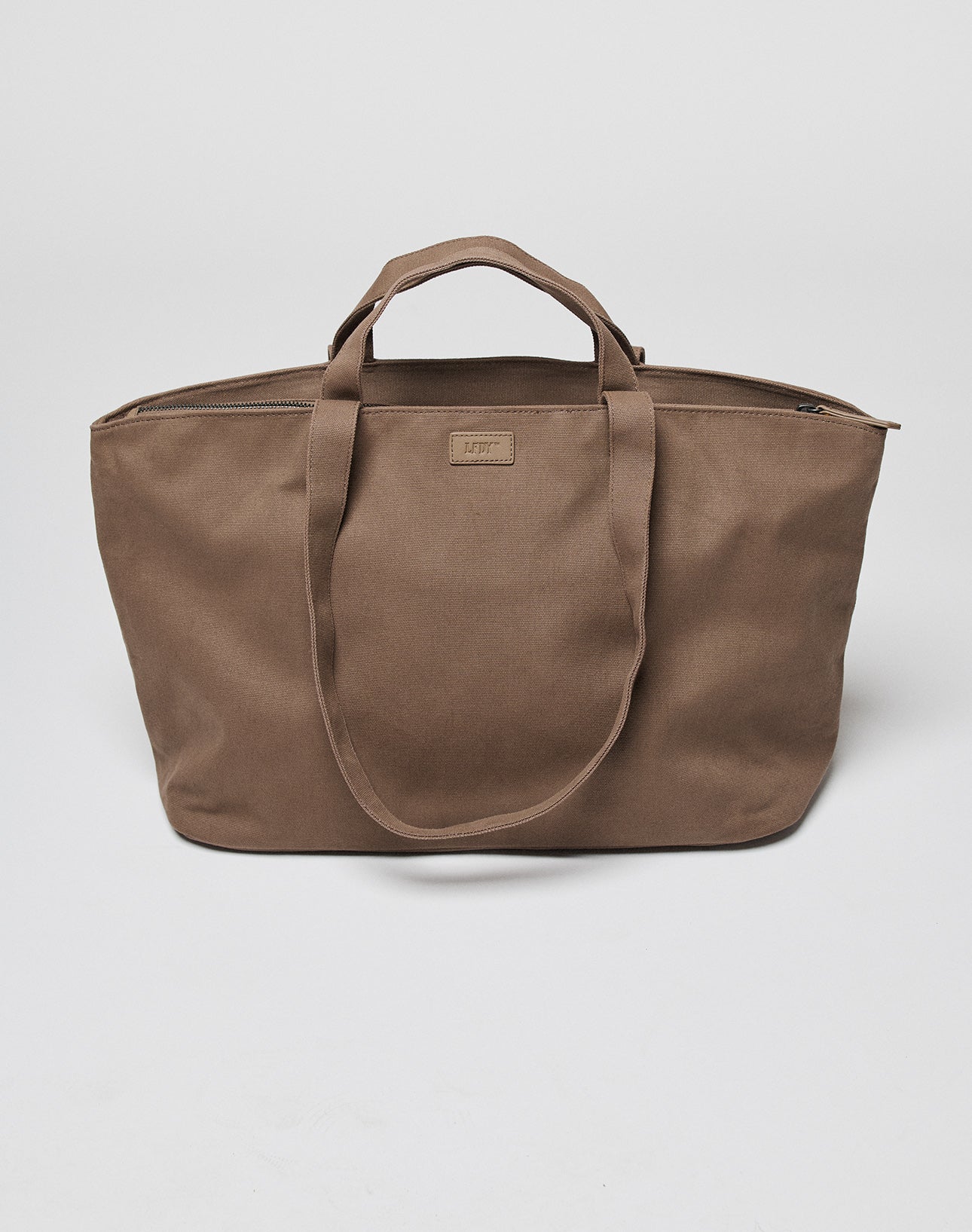 The LFDY Tote Bag by LIVE FAST DIE YOUNG is a large brown canvas Tasche with two short handles, zipper closure, a Laptop Fach, and Rindsleder accents, shown against a plain white background.