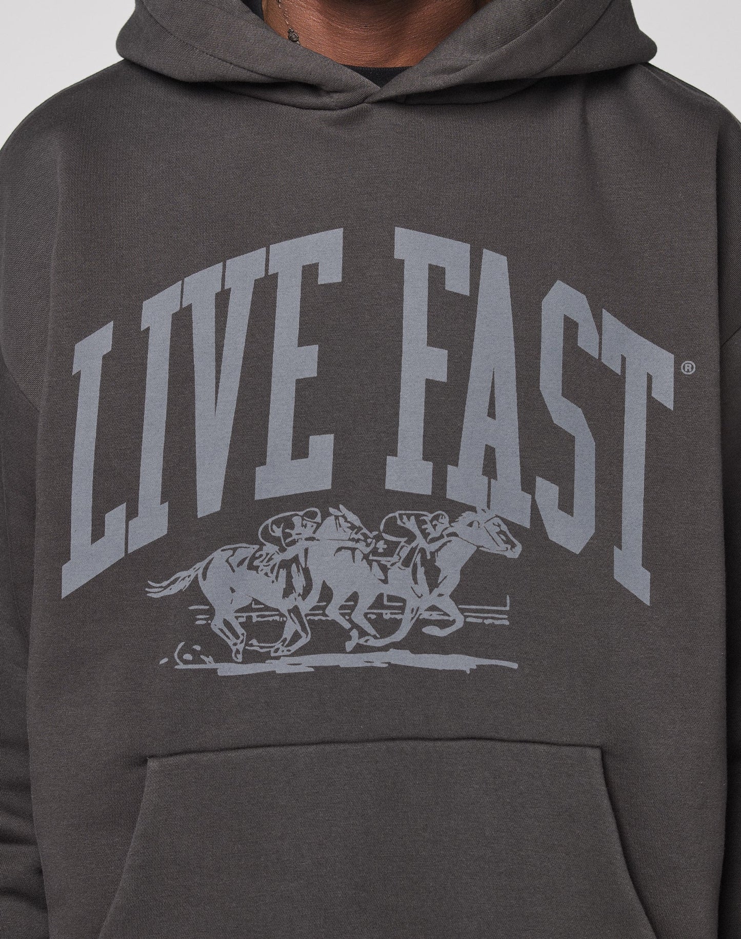 The Live Fast Stallion Hooded by LIVE FAST DIE YOUNG is an oversized charcoal hoodie featuring bold LIVE FAST text above two jockeys on racing horses, crafted from soft Baumwolle cotton.