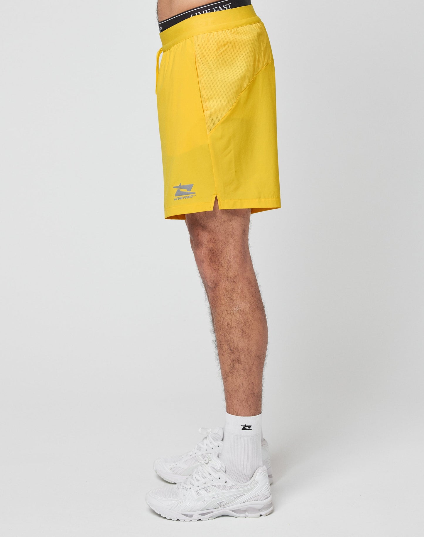 A close-up of the Live Fast Performance Shorts by LIVE FAST DIE YOUNG in yellow, featuring a regular fit and an elastic waistband for comfort.