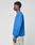 A person stands in profile against a plain background, wearing an oversize fit blue LIVE FAST DIE YOUNG Live Fast Archive Longsleeve and light gray patterned pants.