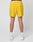 A person is shown from the back against a white background, wearing bright yellow Live Fast Performance Shorts by LIVE FAST DIE YOUNG with Regular Fit, black Elastikbund, and rear pockets, paired with white socks and sneakers.