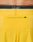 Close-up of the back of bright yellow Live Fast Performance Shorts by LIVE FAST DIE YOUNG, featuring a small zippered pocket and an Elastikbund waistband with black LIVST underwear partially visible above.
