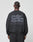 A person with braided hair is seen from behind wearing the Basic Acid Sweater by LIVE FAST DIE YOUNG, an oversized black sweatshirt with bold gray text and vintage-wash details, crafted from a soft cotton-polyester blend.