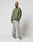 A man wearing the LIVE FAST DIE YOUNG LFDY Wavy Sweater in olive green, a light green ribbed beanie, loose faded jeans, and white sneakers stands against a plain white background.
