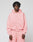 A person with short, curly hair wears the Basic Hooded Zip in light pink by LIVE FAST DIE YOUNG, paired with matching sweatpants featuring subtle branding. They face the camera against a plain light gray background with a neutral expression.