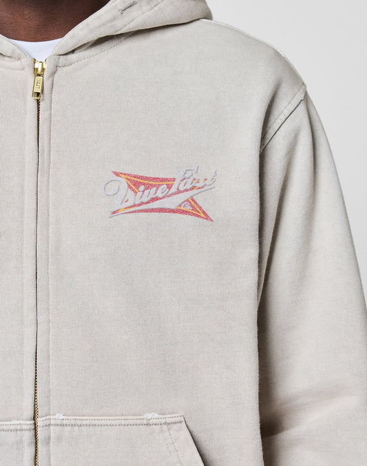 A person wearing a LIVE FAST DIE YOUNG LFDY Corp. Hooded Zip in light beige 100% Baumwolle with a gold zipper, featuring a small colorful graphic and "Time Flies" on the left chest. Only the upper torso is visible.