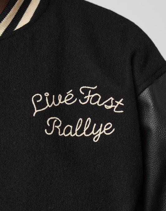 Close-up of the LFDY x Schott NYC Varsity Jacket by LIVE FAST DIE YOUNG, featuring cream Livé Fast Rallye embroidery on the chest, a black leather sleeve, and a striped collar.