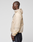 A man in profile wears the LIVE FAST DIE YOUNG Live Fast Nylon Jacket in light beige with reflective print and dark pants, set against a plain light gray background.