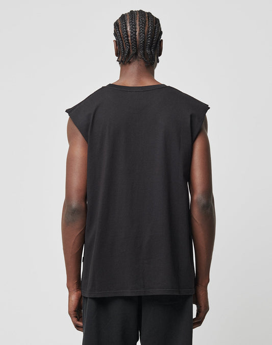 A person with braided hair, seen from behind, wears the LIVE FAST DIE YOUNG Basic Muscle Shirt aus 100% Baumwolle and black Loose Fit pants against a plain light background.