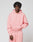 A person in a light pink LIVE FAST DIE YOUNG Basic Hooded Zip and matching sweatpants stands against a plain light gray background, with short textured hair and a neutral expression.