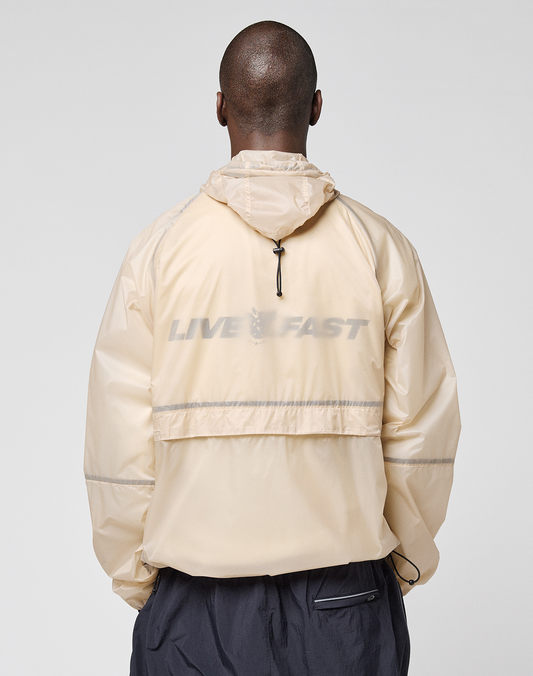 A person is shown from behind wearing the LIVE FAST DIE YOUNG Live Fast Nylon Jacket in light beige, featuring a reflective LIVE FAST print on the back, set against a plain light background.