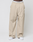 Someone wearing LIVE FAST DIE YOUNG Baggy Nylon Pants in beige with an elastic waistband, paired with white sneakers and visible LIVE FAST branded underwear, stands against a plain light background.