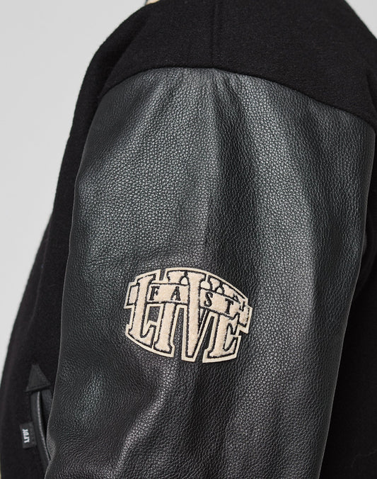 Close-up of a black LFDY x Schott NYC Varsity Jacket sleeve with textured leather and a beige LIVE FAST DIE YOUNG patch. This Limited Edition piece blends classic style with bold, standout details.
