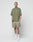A man with short hair and visible tattoos wears an oversized olive green t-shirt and LIVE FAST DIE YOUNG Basic Mesh Shorts in olive green with elastic waistband, paired with white crew socks and sneakers. He stands against a plain white background, hands in his pockets.