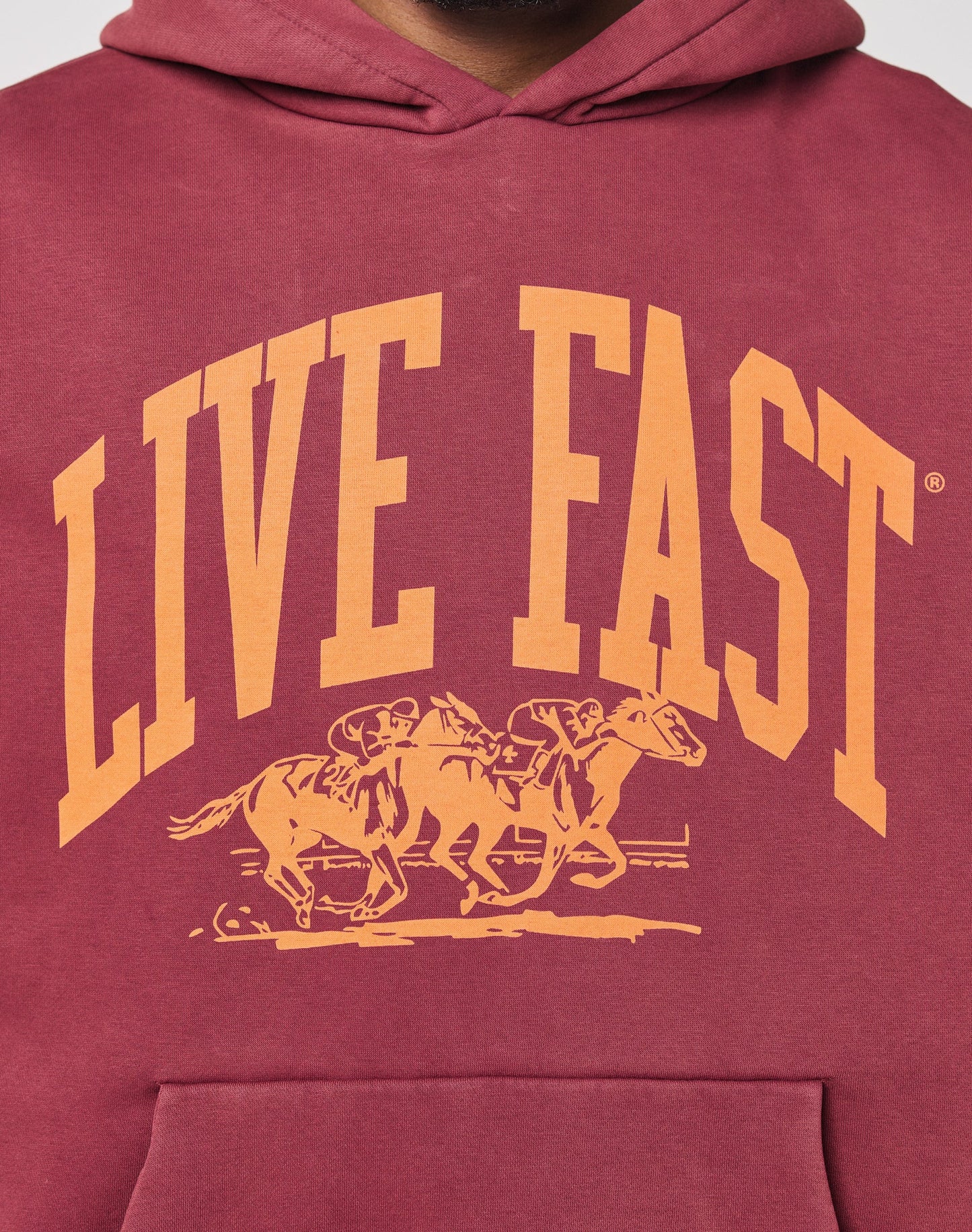 The Live Fast Stallion Hooded by LIVE FAST DIE YOUNG is a maroon, oversized hoodie with a bold yellow front print of two jockeys racing under the words LIVE FAST. Crafted from soft Baumwolle for comfort all day.