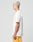 A person with short blond hair stands in profile, wearing a plain white LIVE FAST DIE YOUNG LFDY Fries Tee and yellow mesh shorts. Their tattooed arm is visible against a plain light gray background. Style: LF2406-15695.