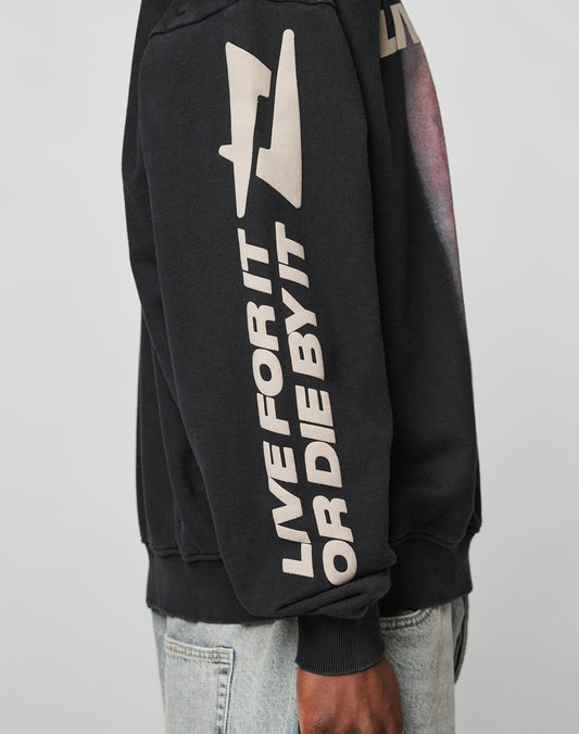 Wearing the black LFDY Angel Sweater by LIVE FAST DIE YOUNG, with bold beige LIVE FOR IT OR DIE BY IT sleeve text, a lightning bolt graphic above, and a subtle distress effect for added style.