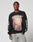 A man wears the LFDY Angel Sweater by LIVE FAST DIE YOUNG, an oversized black cotton sweatshirt with LIVE FAST text, a colorful abstract graphic, and white sleeve detail. He pairs it with light-wash jeans against a gray background.