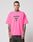 A man with tattoos wears the LFDY Triple Racing Tee by LIVE FAST DIE YOUNG—an oversize, bright pink 100% cotton T-shirt with a bold multilogo LIVE FAST front print—standing against a plain light gray background.