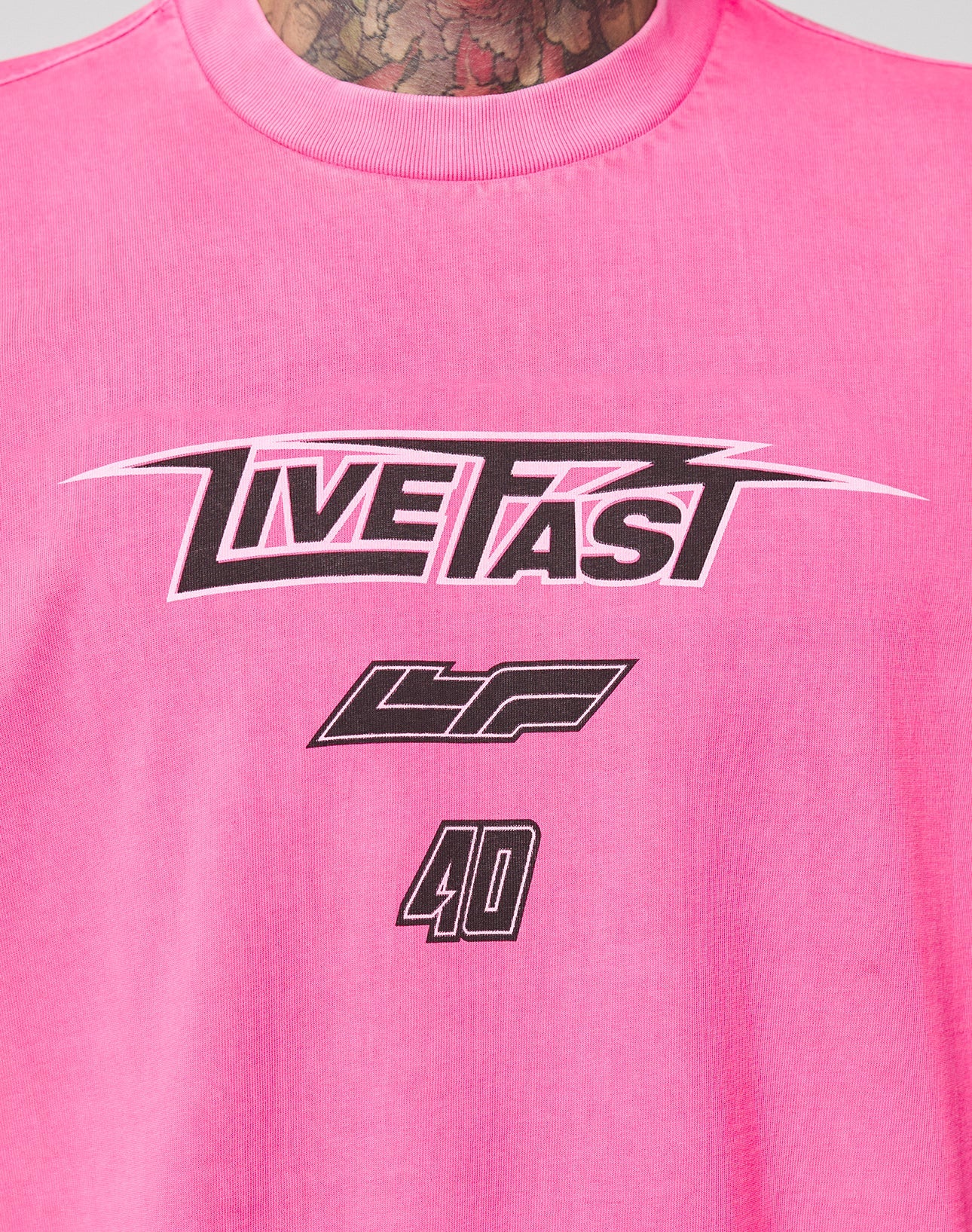 The LFDY Triple Racing Tee by LIVE FAST DIE YOUNG features a pink, oversize fit, 100% Baumwolle design. It sports a multilogo frontprint: LIVE FAST in bold black and white, with LF and the number 40 below for standout style and comfort.