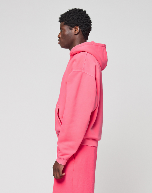 A young man stands in profile, wearing a bright pink LIVE FAST DIE YOUNG Basic Hooded Zip and matching pink shorts with subtle branding, set against a plain light gray background.