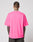 A person with short hair and visible tattoos on their neck and arms is shown from the back, wearing the bright pink LFDY Triple Racing Tee by LIVE FAST DIE YOUNG, styled with dark pants against a plain light background.